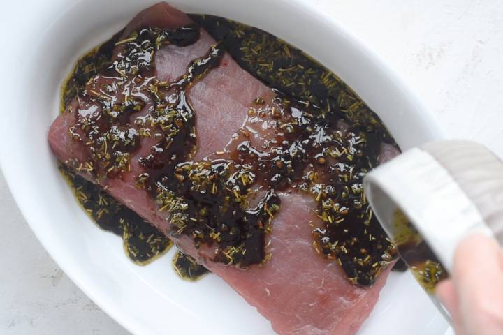 Flank steak being marinated with balsamic vinegar, garlic, and spices.