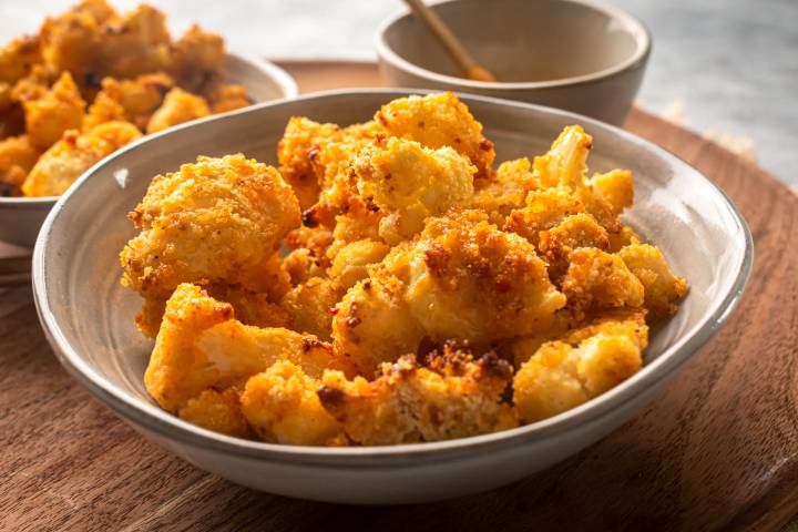 Bang bang cauliflower after being broiled until crispy served in a bowl.