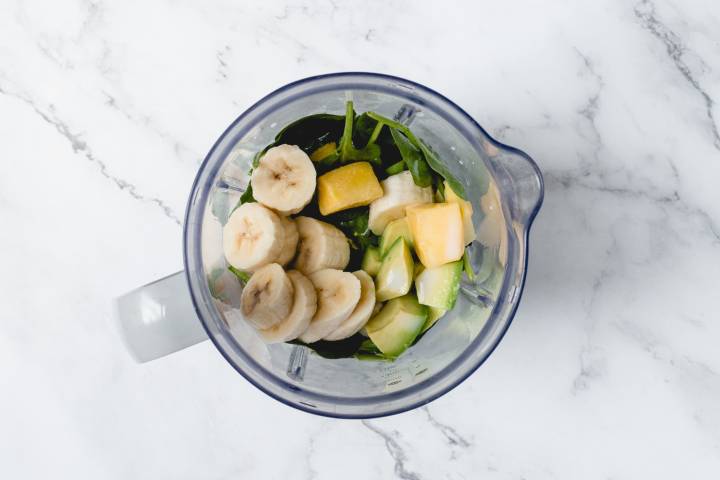 Spinach, mango, banana, and avocado in a blender.