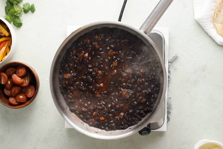 Black beans and salsa simmering in a skillet.