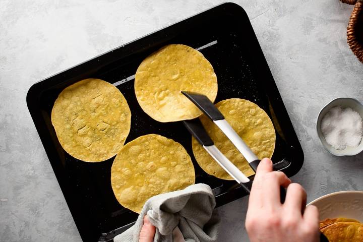 Corn tortillas on a baking sheet for tostadas.