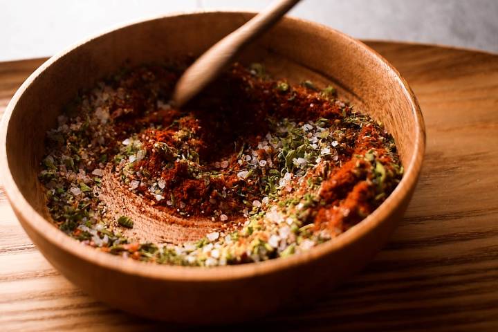 Homemade blackening seasoning being stirred in a wooden bowl.