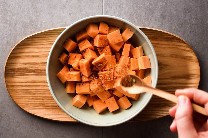 Sweet potatoes being tossed with blackening seasoning.