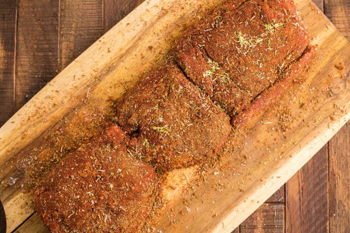 Beef tenderloin covered in blackening seasoning on a cutting board.