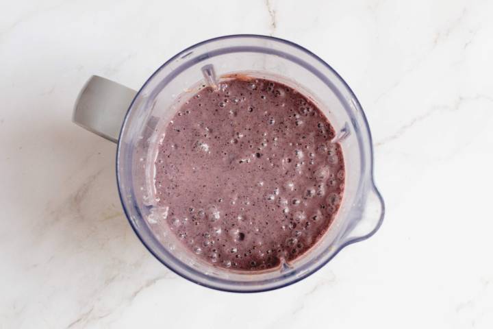 Blended blueberry banana smoothie in a blender.
