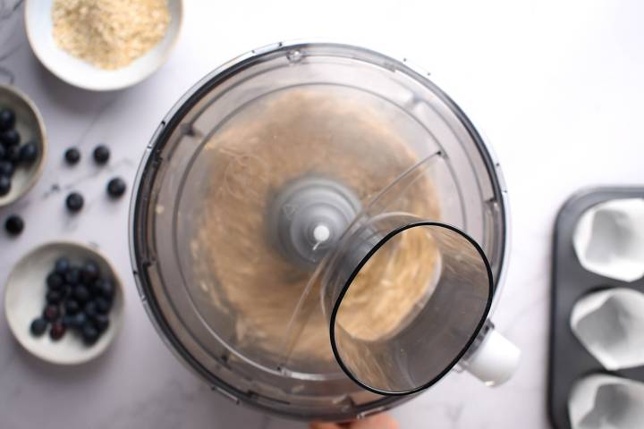 Oats being pulsed into flour in a food processor.