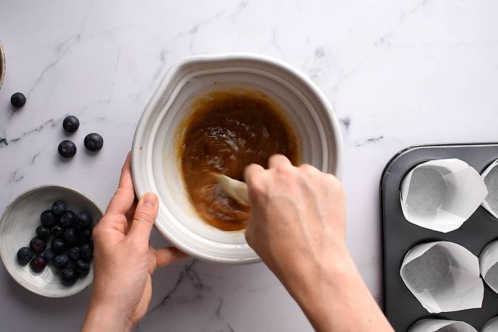 Brown sugar, honey, applesauce, egg whites, oil, and vanilla being stirred in a bowl.