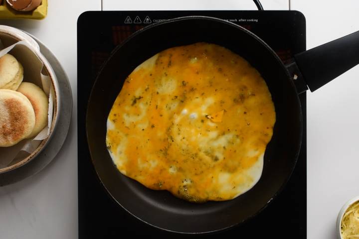 Scrambled eggs in a skillet with Italian seasoning, salt, and pepper.