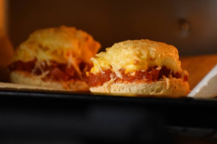 English muffin breakfast pizza in the oven with melted cheese.