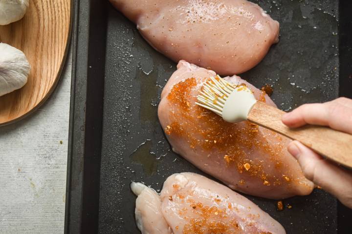 Chicken breasts being coated with brown sugar and butter.