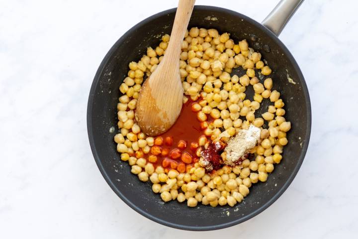 Chickpeas in a skillet with butter, buffalo sauce, and spices.