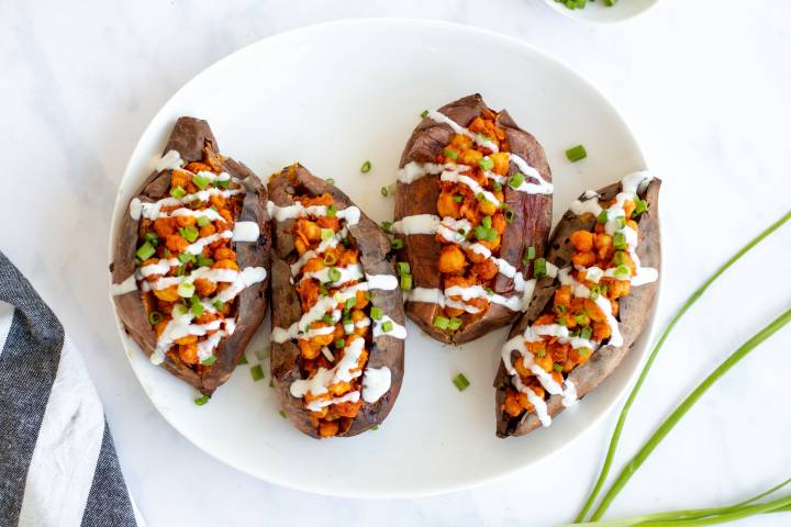 Stuffed sweet potatoes with buffalo chickpeas and ranch dressing.