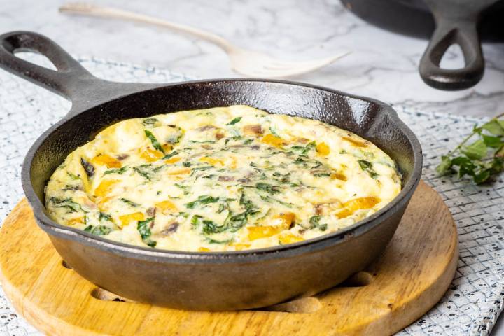 Baked butternut squash, egg, and spinach casserole in a skillet.