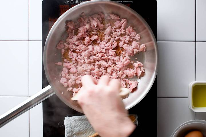 Ground turkey sausage browning in a skillet.