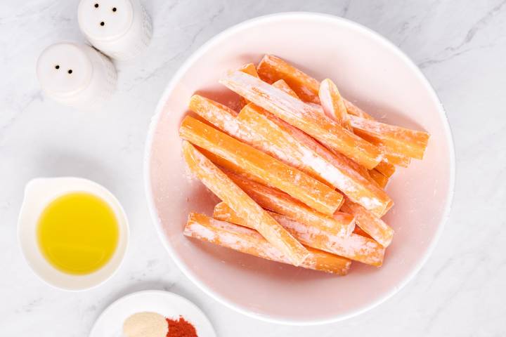 Squash fries tossed with cornstarch in a white bowl.
