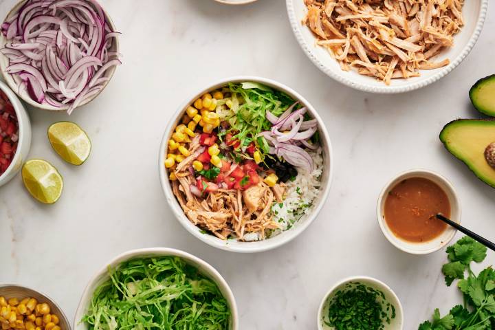 Carnitas bowl with cilantro, lime, red onion, pico de gallo, and avocado.