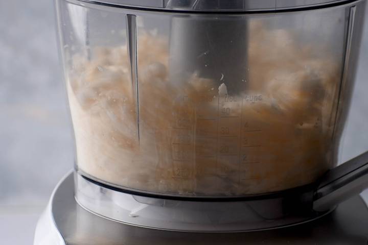 Food processor with cauliflower being pulsed into rice like pieces.