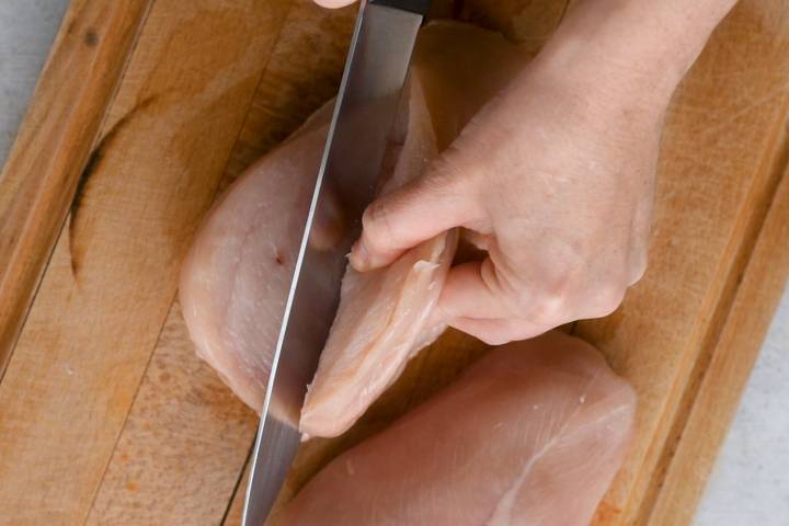 Cutting a slit in the raw chicken breast for the stuffing.