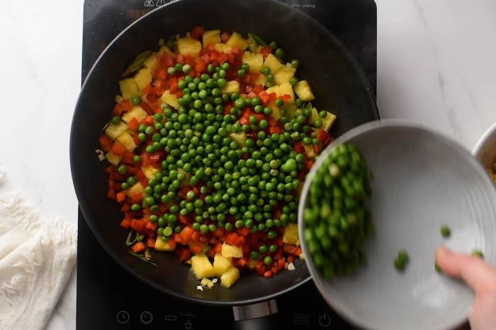 Pineapple, peas, carrots, red peppers, garlic, and ginger in a skillet.