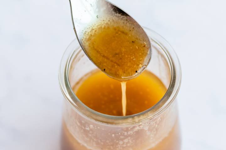 Honey lime salad dressing in a small glass jar with a spoon.