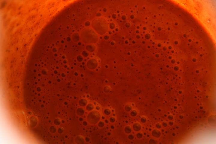 Achiote paste, lime juice, orange juice, and spices in a blender.