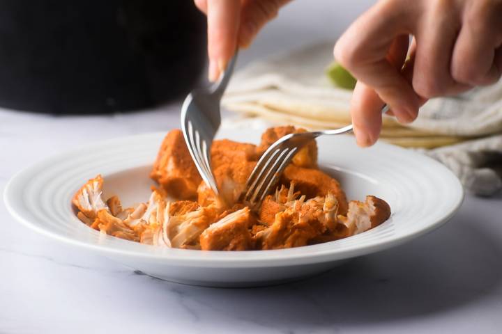 Tow forks shredded cochinita pibil pork in a bowl.