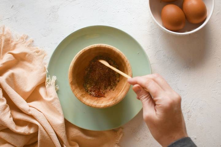 Spice mixture being stirred in a small wooden bowl.