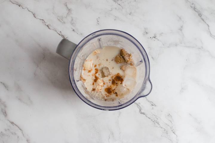 Oatmeal smoothie ingredients in a blender with milk, bananas, and oats.