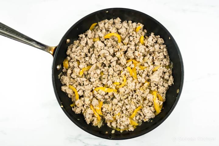 Ground chicken, peppers, and onions in a pan.