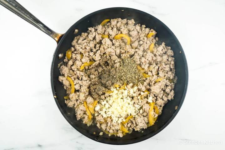 Ground chicken with garlic, Italian seasoning, and black pepper in a pan.
