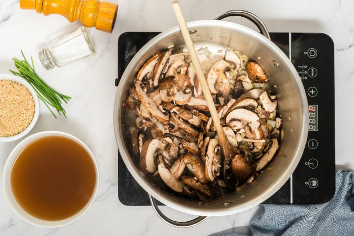 Mushrooms and thyme cooking in a pot with onions and garlic.