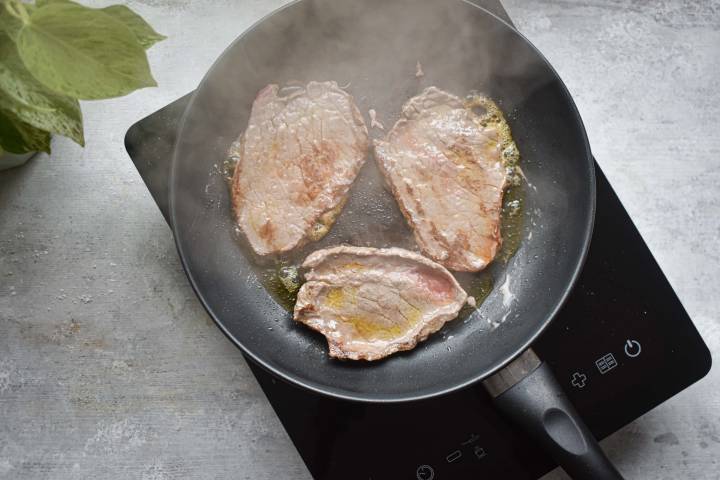 Steak cooking in a pan.