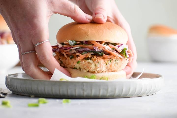 Salmon burgers on hamburger bun with shredded coleslaw.