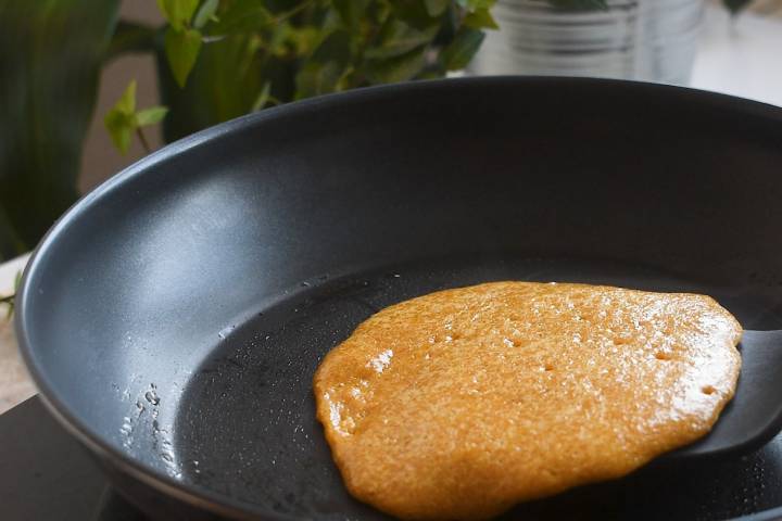 Flax pancake being flipped in a skillet.