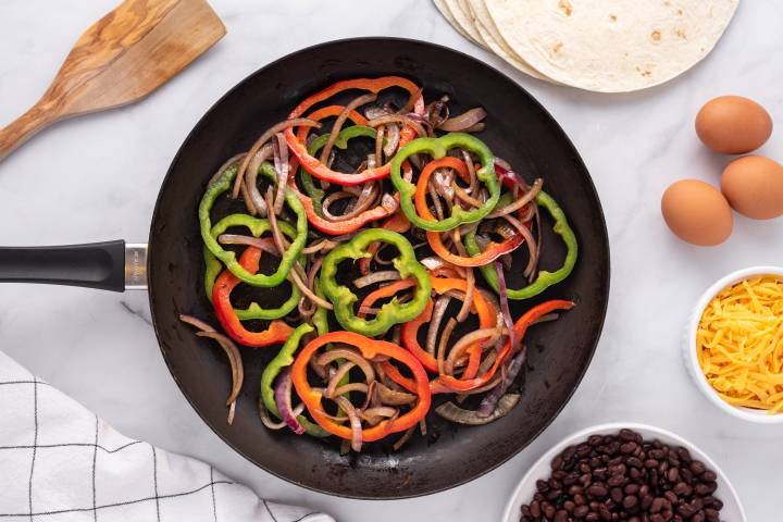 Peppers and onions cooking in a skillet.