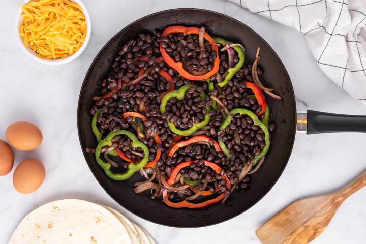 Black beans, peppers, and onions in a skillet.