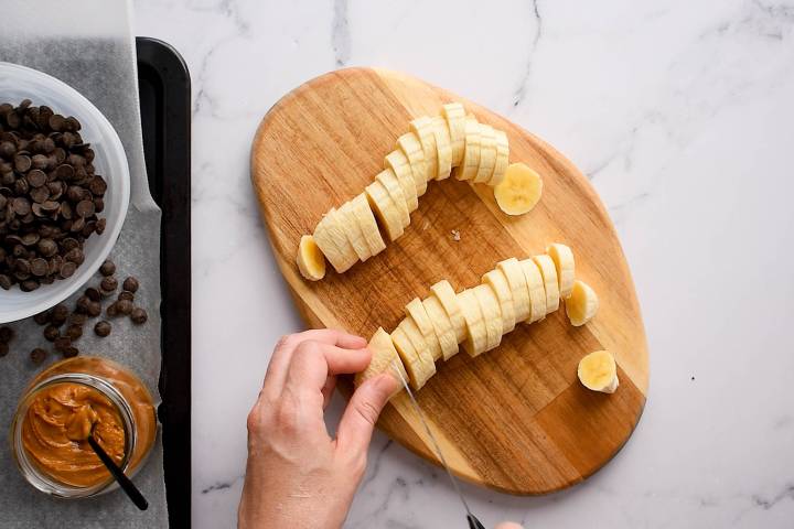 Bananas being sliced on a cutting board.