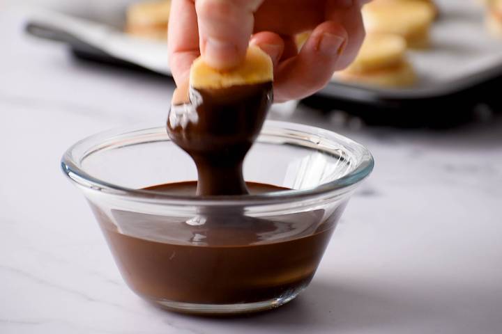 Banana peanut butter sandwiches being dipped in chocolate.