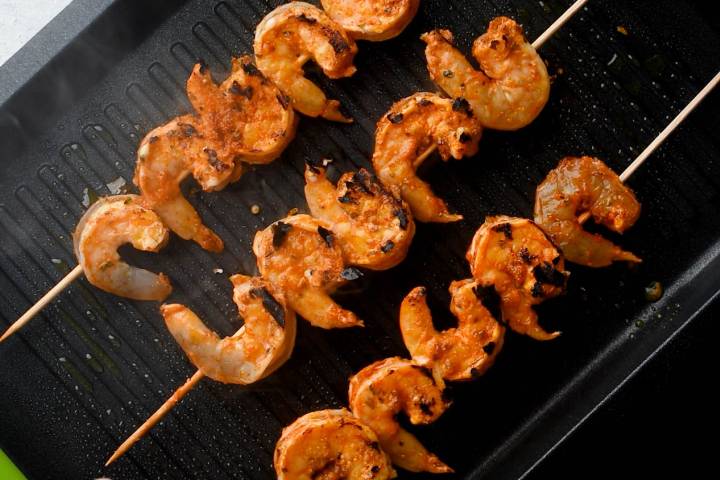 Shrimp being grilled on skewers on a grill pan.