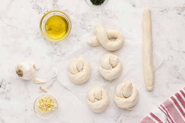 Two ingredient dough being rolled in knots on a marble board.