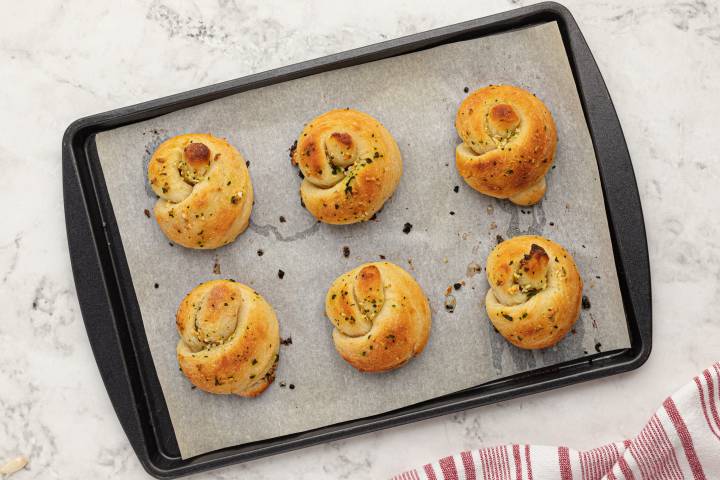 Baked golden brown garlic knots on a baking sheet.