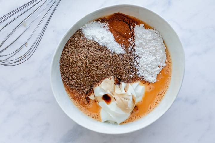 Flaxseed meal., eggs, Greek yogurt, cinnamon, and baking powder in a bowl.