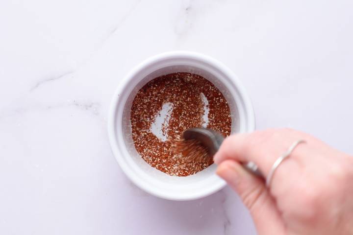 Paprika, garlic powder, onion powder, cumin, salt, and pepper in a white bowl.