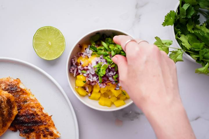 Cilantro being added to a pineapple salsa. 
