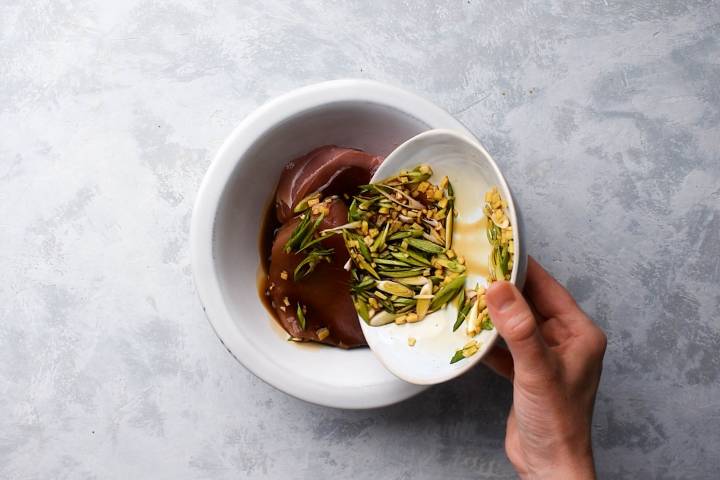 Ahi tuna steaks marinating in a bowl.