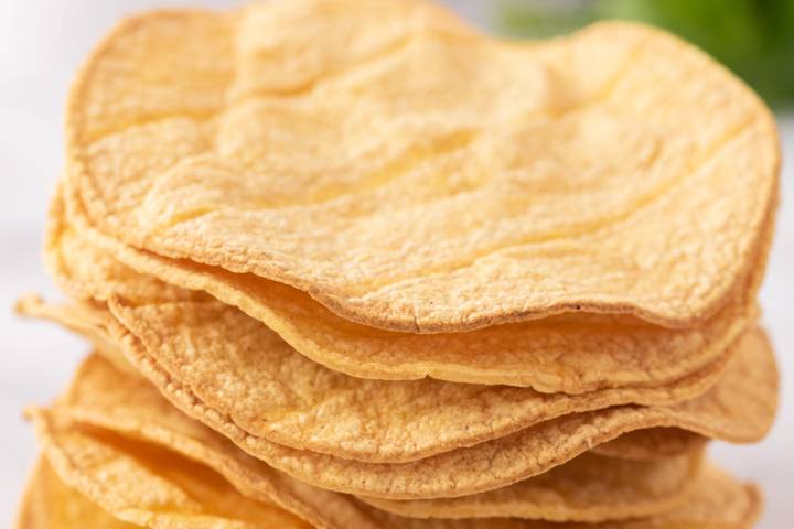 Homemade crispy tostada shells stakced in a pile.