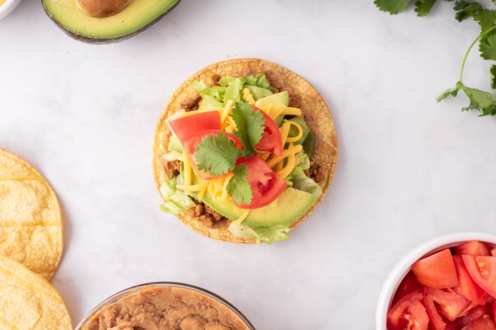 Ground turkey tostadas with refried beans, lettuce, tomatoes, and cilantro.