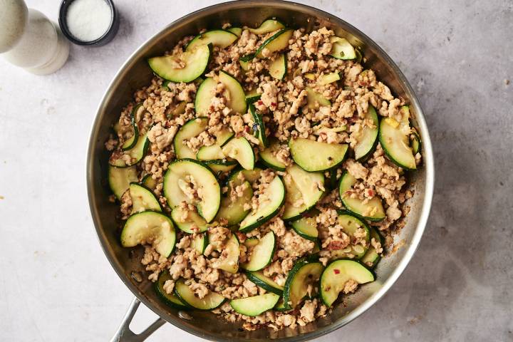 Ground turkey and zucchini stir fry in a stainless steel skillet, cooked with garlic and seasonings until golden and tender.