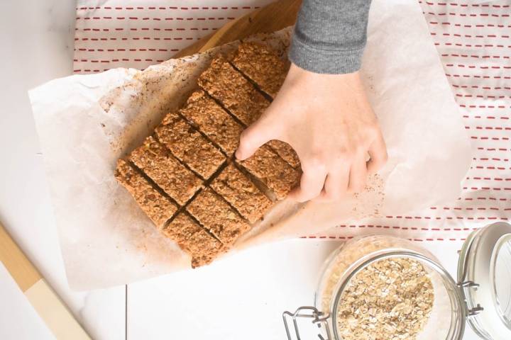 Peanut butter oatmeal bars being cut into bars on parchment paper.