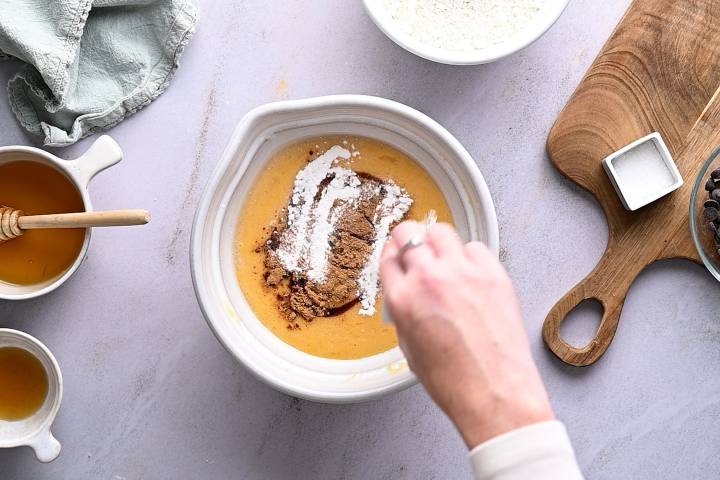 Baking soda and cinnamon being added to a bowl of pumpkin and banana.